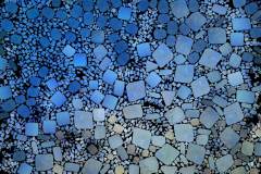 Farbiges Mosaik,  bestehend aus vielen kleinen, unregelmäßig geformten Steinchen.